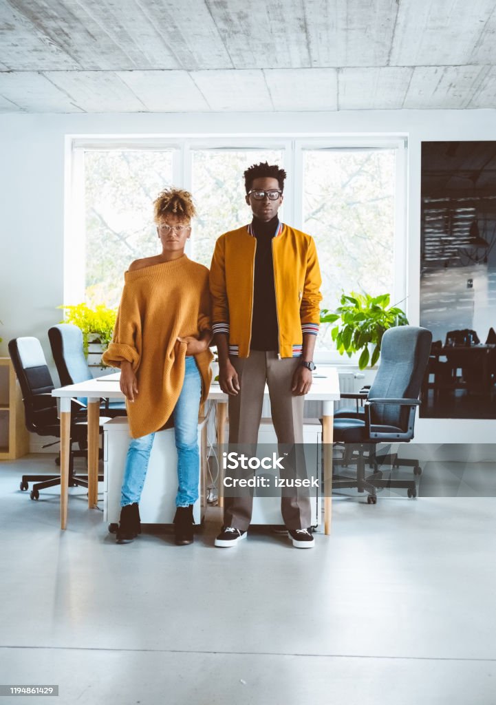 Confident business people in casuals at startup office Portrait of two business partners standing in office and looking at camera. Confident business people in casuals at startup office. Small Business Stock Photo