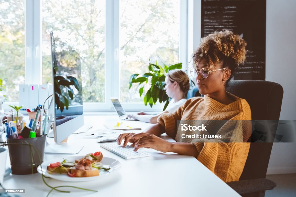 Business professionals working in office Shot of a african businesswoman working on desktop computer. Business professionals working in office. 30-34 Years Stock Photo