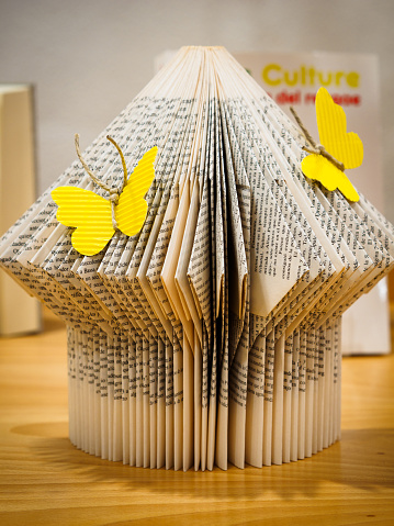 Pages of a book folded to shape it with decorative butterflies. Reading concept. (translation: culture)