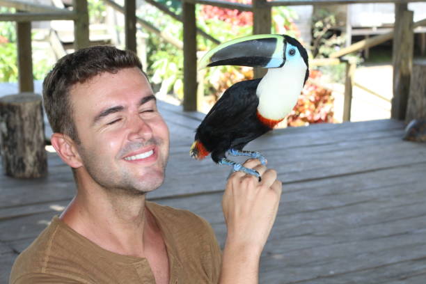 istock Cheerful man with eyes closed holding a toucan 1194864389