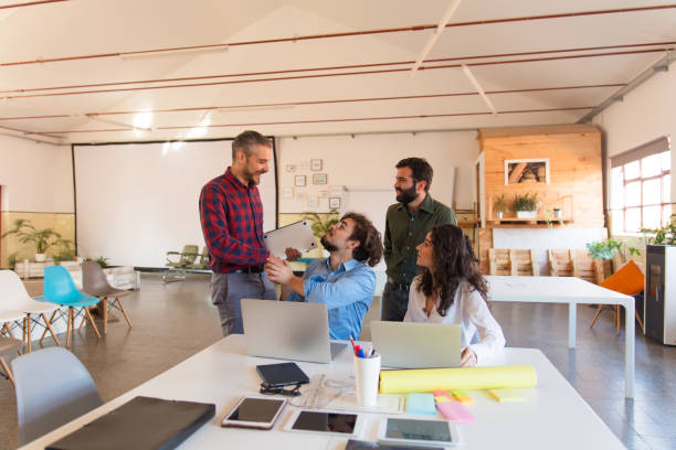 istock Positive startup group with laptops chatting in meeting room 1194865571