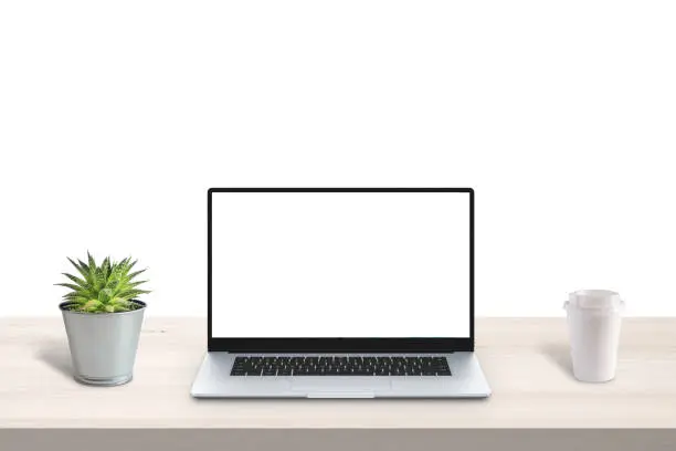 Simple, modern laptop with isolated screen for mockup on office desk. Plant and cup of coffee beside. White background, copy space