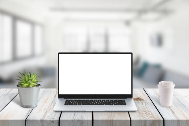 istock Laptop computer on wooden desk with isolated screen for app or web site promotion. Office in background. Plant and cup of coffee on desk 1194867154