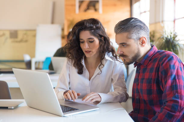 istock Serious coworkers discussing project and using laptop together 1194869491