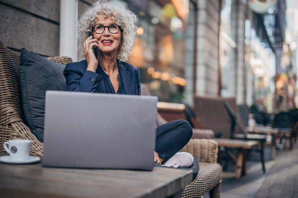 istock Senior lady talking on mobile outdoors in cafe 1194869614