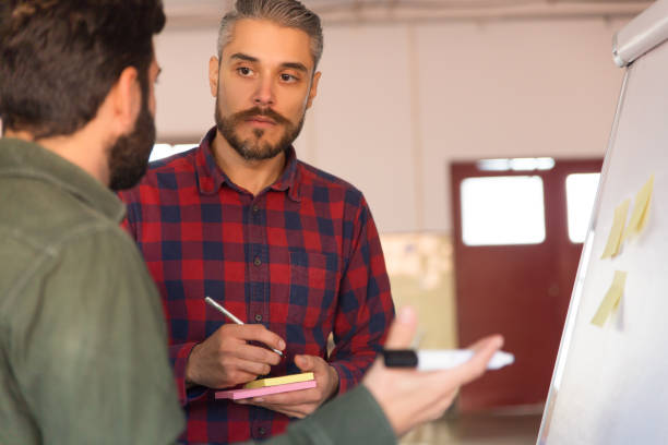 istock Male coworkers standing at flipchart 1194869616