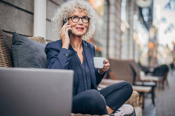 istock Senior woman talking on mobile outdoors in cafe 1194869627