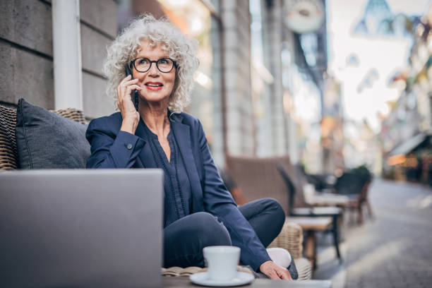 istock Mature lady talking on mobile outdoors in cafe 1194869649