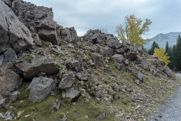 istock Harsh rock formations creating rough hill next to gravel road with fall colors 1194869865