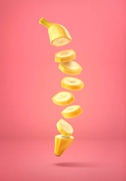 Flying fresh ripe banana cut into slices on pink background