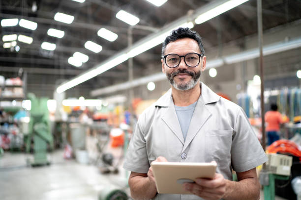 ritratto di un dipendente che utilizza un tablet digitale in una fabbrica - operaio di produzione foto e immagini stock