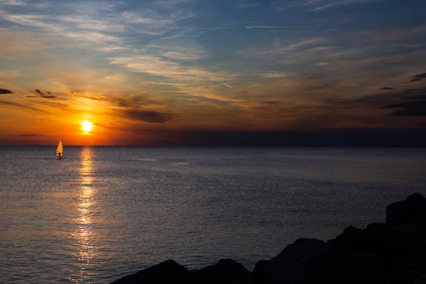istock Lonely Wind surfer setting sail towards the dramatic and magnificent scenic sunset at the coast of the mediterranean sea in Trieste, Italy 1194877420