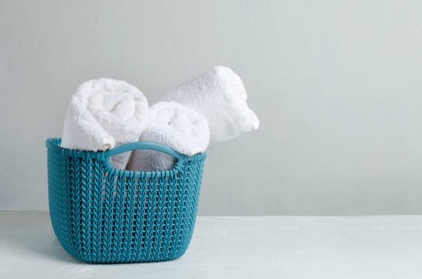 istock Blue basket full of fresh white towels on the table against bright wall.Empty space for text 1194877649