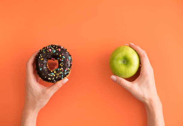 Donut or Apple Healthy Eating, Unhealthy Eating, Apple - Fruit sugar food stock pictures, royalty-free photos & images