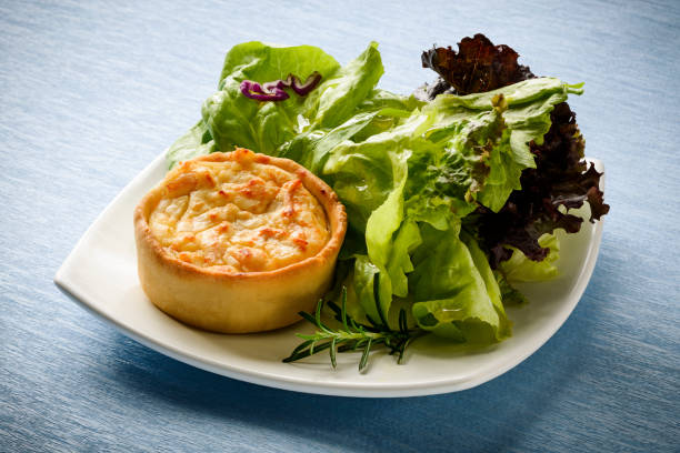 eine kleine quiche mit einem beilagensalat. - spinach quiche tart savory food stock-fotos und bilder