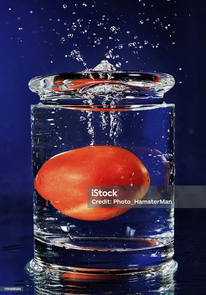 レッドトマトフォーリングダウンのガラスに水 - しずくのロイヤリティフリーストックフォト