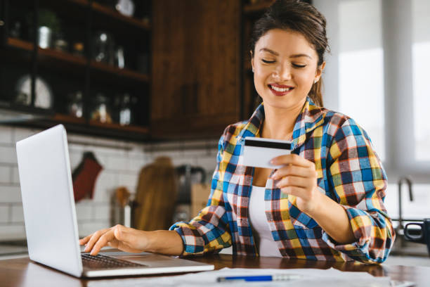 istock Young woman holding credit card and using laptop computer 1194888220