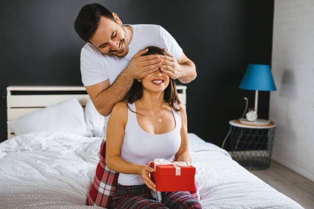 istock Man surprising his girlfriend in bed with a gift 1194888582