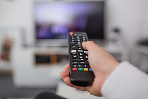 Ver la televisión y usar el mando a distancia. Mano con mando a distancia cambiando canales o abriendo aplicaciones en smart tv photo