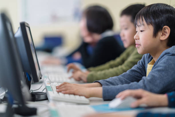 Portrait of elementary school girl while taking computer classes A portrait of an elementary school girl while taking computer classes with her other friends in a computer lab in an Elementary school building. japanese boy and girl stock pictures, royalty-free photos & images