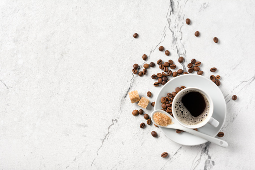 Top view of black coffee in white cup with sugar for breakfast on marble background with copy space