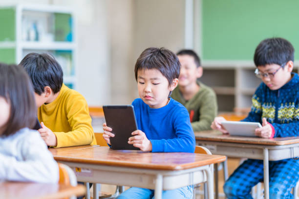 教室でデジタルタブレットを使用する学校の子供たち - 小学生 ストックフォトと画像