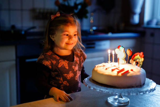 menina adorável da criança pequena que comemora o terceiro aniversário. criança da criança do bebê com bolo caseiro do unicórnio, interno. a criança saudável feliz é surpreendida sobre o sparkler do fogo-de-artifício e velas de sopro no bolo - birthday cake family germany indoors - fotografias e filmes do acervo