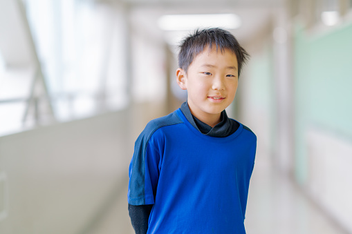 A portrait of a happy elementary school schoolboy in hallways.