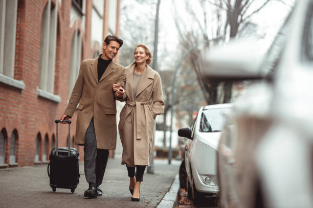 Ready for a trip Smiled smart elegant couple is walking to the car in the street. He is pulling the suitcase and unlocking the car with the remote key. georgijevic frankfurt stock pictures, royalty-free photos & images