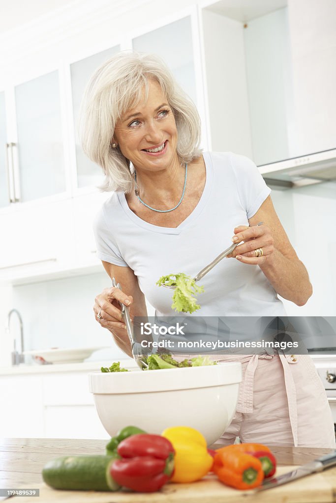 Mujer Senior ensalada de preparación en la cocina - Foto de stock de 60-69 años libre de derechos