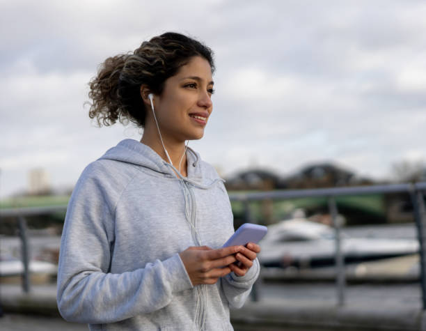 istock Runner outdoors using her cell phone and listening to music 1194895510