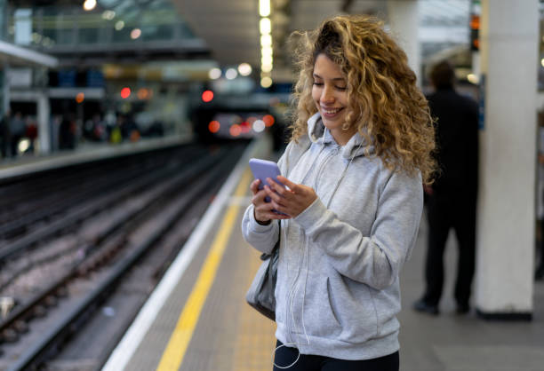 istock Woman looking at her cell phone while waiting for the train 1194895538