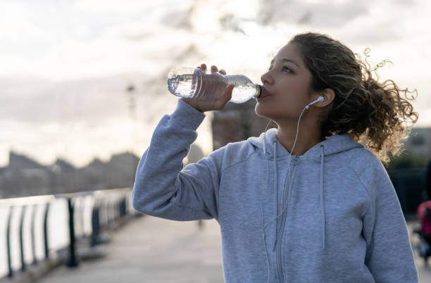 istock Woman drinking water while running outdoors 1194895543