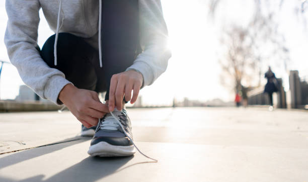 istock Close-up on a runner tying her shoelaces outdoors 1194895564