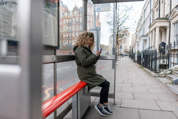frau soziale netzwerke beim warten auf den bus - london england england bus uk stock-fotos und bilder