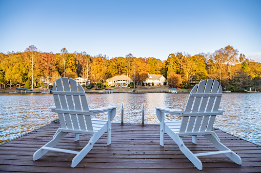 Adirondack style chairs on a dock, overlooking a beautiful, quiet, lake. Concept of a relaxing vacation in a remote area.