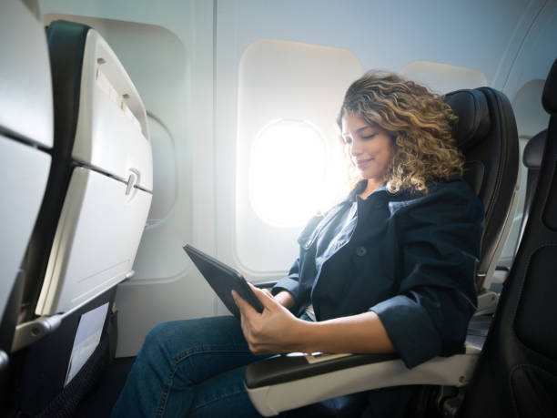 istock Young beautiful female using her tablet during a commercial flight smiling 1194896969