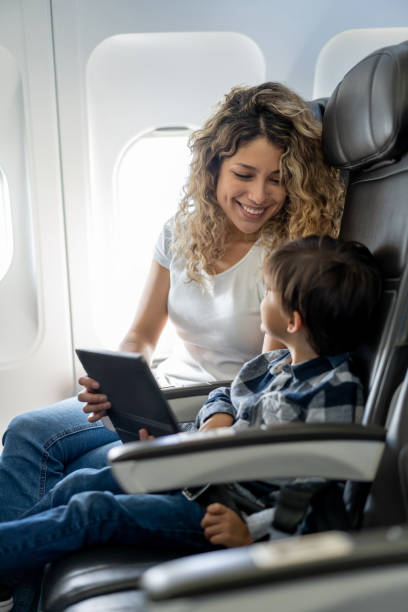istock Loving mother and son looking at each other while playing on tablet during a commercial flight 1194896978