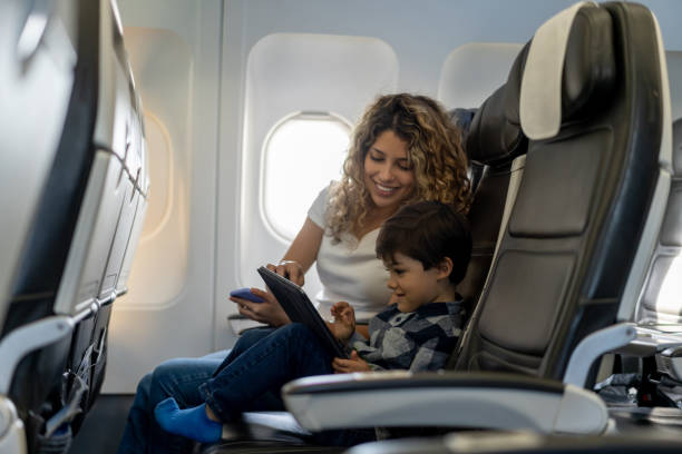 Loving mother and son playing with tablet during a flight looking very happy