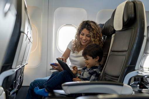 Loving mother and son playing with tablet during a flight looking very happy and smiling