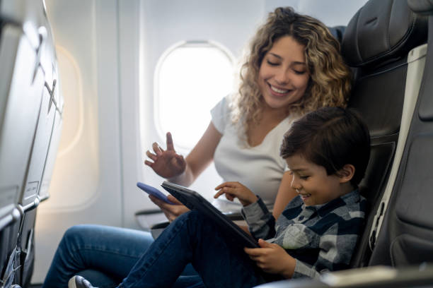 istock Latin american boy and mother smiling and laughing while playing on tablet during a commercial flight 1194897000