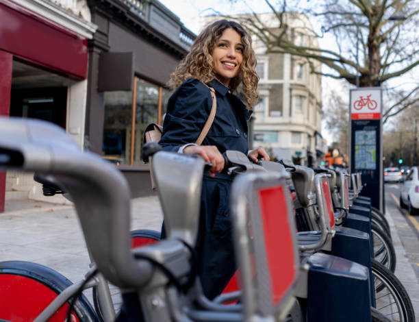 hermosa joven alquilando una bicicleta de la ciudad sonriendo - bikeshare fotografías e imágenes de stock