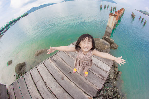 Little girl posing for the camera while one is smiling at beach side in a sunny park