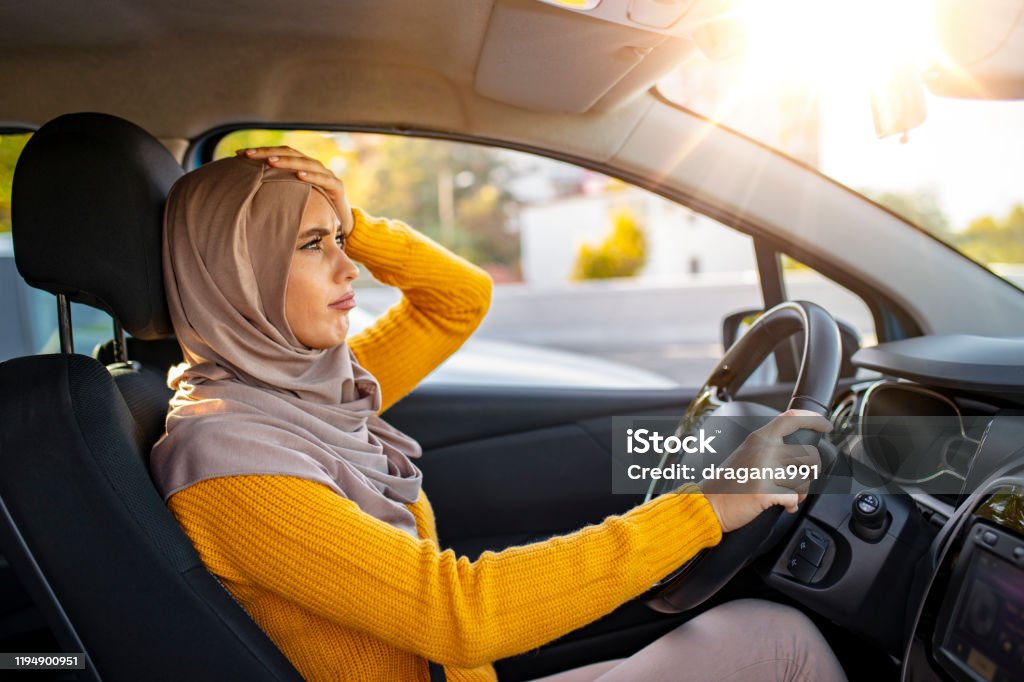 Muslim Woman is driving her car very aggressive Closeup shot of stressed young Muslim woman driver in a car. Angry and tense Muslim woman stuck in the traffic.  Stressed woman driver sitting inside her car Driving Stock Photo