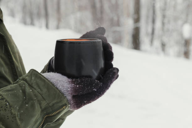 istock Hands in warm gloves hold a mug with a hot drink. 1194904265