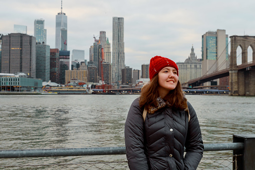 View from back of traveling beautiful young girl on Brooklyn Bridge with Manhattan skyscrapers on background