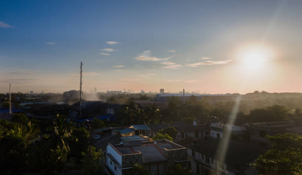 Wide panoramic HDR view of Colombo city skyline during sunset on a clear day from Wattala side, Sri Lanka. Harbor, lotus tower & other highrises are visible in background with houses in foreground stock photo
