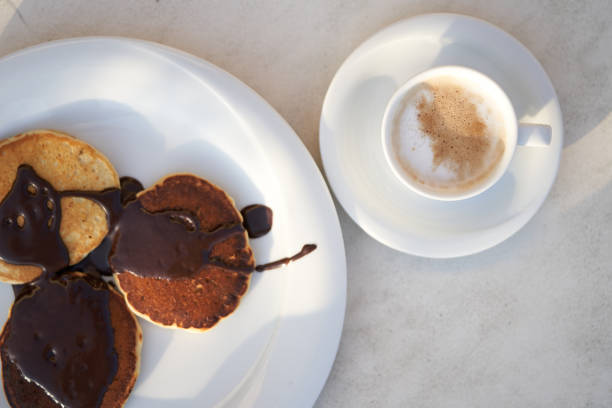 istock Freshly cooked chocolate pancakes poured on a white plate with a cup of fresh coffee. Balanced breakfast. Energy charge. View from above 1194907356