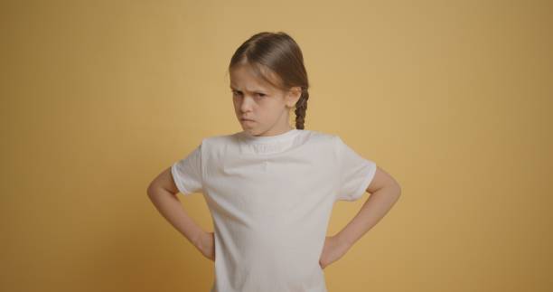 la bambina in maglietta bianca si arrabbia con il muro giallo sullo sfondo - impatient children only child anger foto e immagini stock