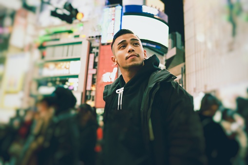 Young asian man looking away at the night time in Tokyo
